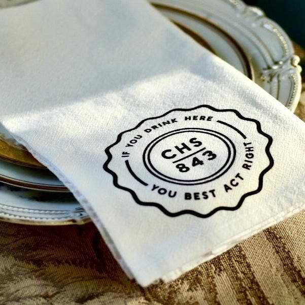 The Charleston Dinner Napkin folded on a plate, hand-printed cotton flour sack napkin